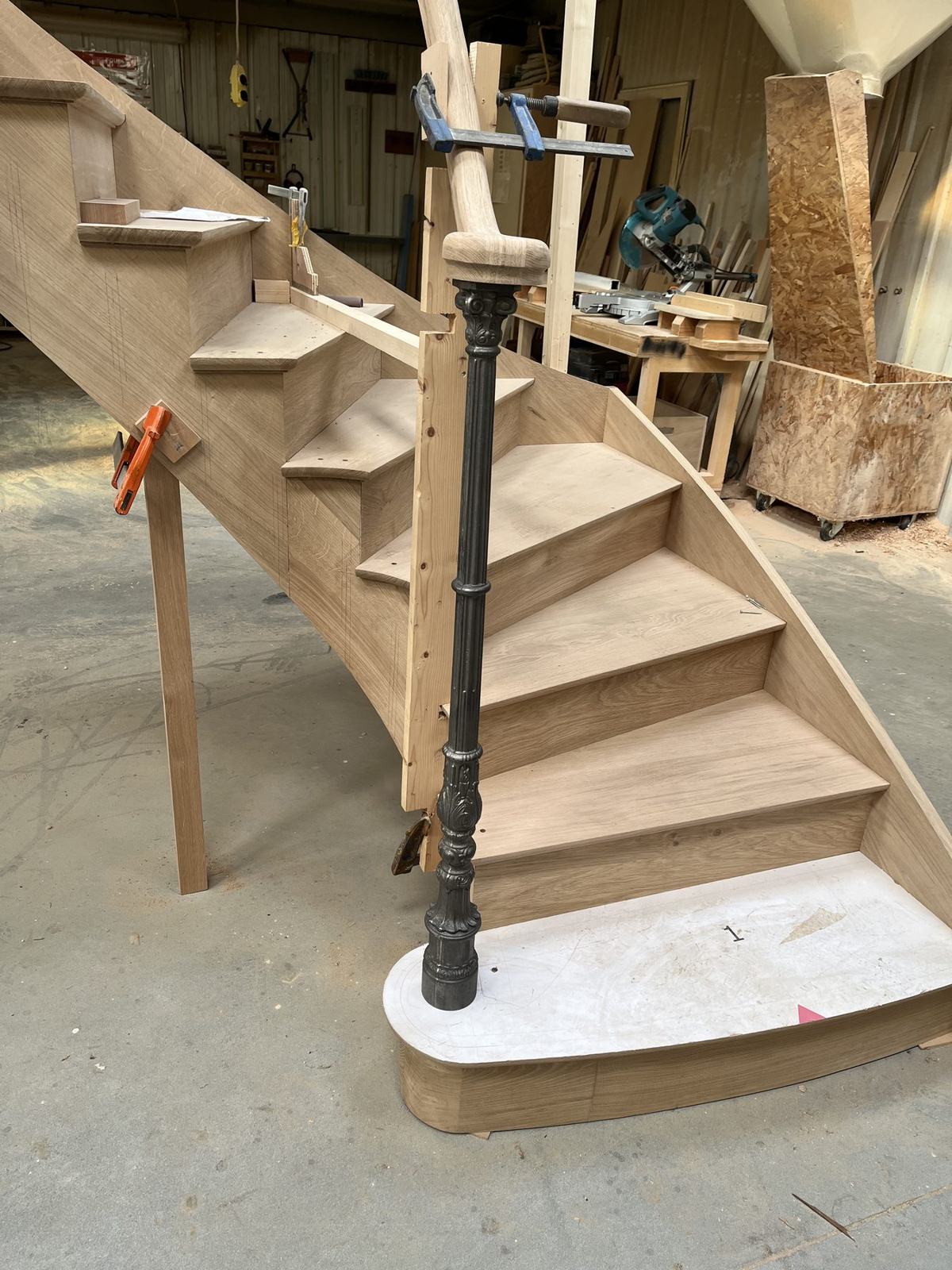 Départ d’escalier en chêne, marche galbée et poteau en fonte