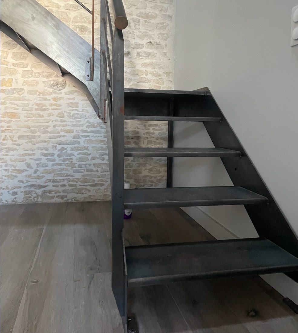 Escalier métallique noir le long d’un mur de pierre