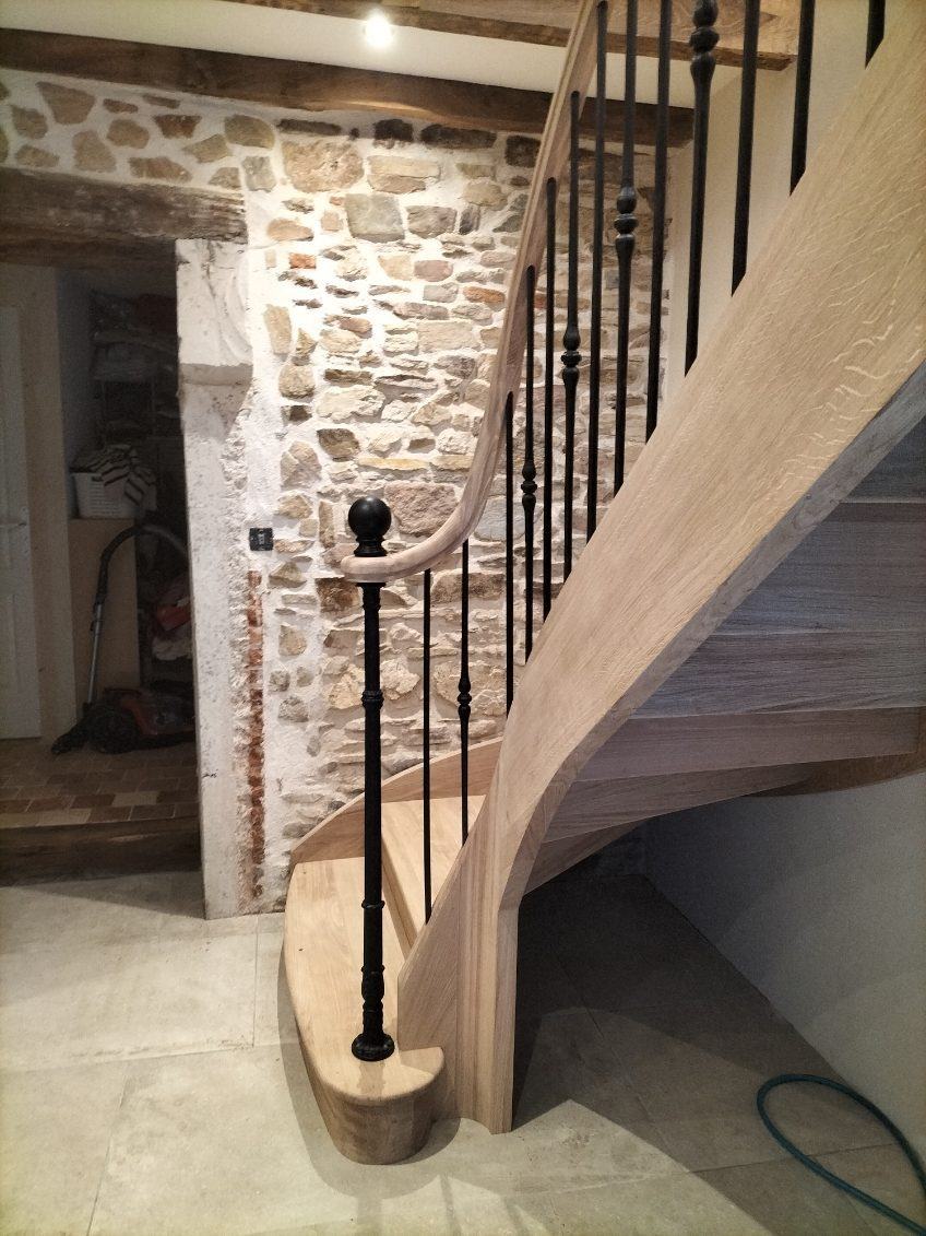 Escalier en chêne le long d’un mur de pierre, balustres en fer forgé